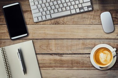 Ofis masaları ile kahve fincanı, bilgisayar, telefon, not defteri ve kalem.