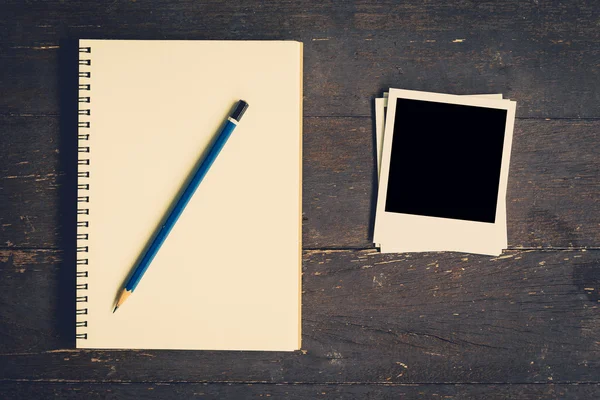 Notebook and pencil with frame photo on wood table background wi — Stock Photo, Image