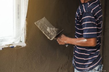 İşçi eli duvara mala yapıştırıyor.