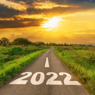 Boş asfalt yol ve yeni yıl 2022 konsepti. 2022 hedeflerine giden boş bir yolda gün batımına doğru sürüyorum..