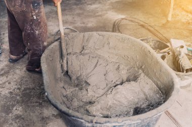 İşçi evi inşaatçısı kovadaki bir yalaktan havan topu karıştırıyor.