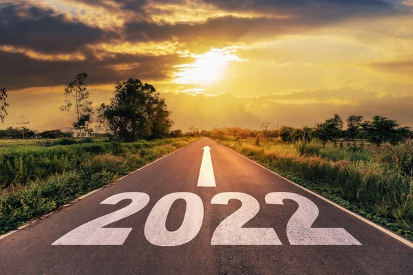 Boş asfalt yol ve yeni yıl 2022 konsepti. 2022 hedeflerine giden boş bir yolda gün batımına doğru sürüyorum..