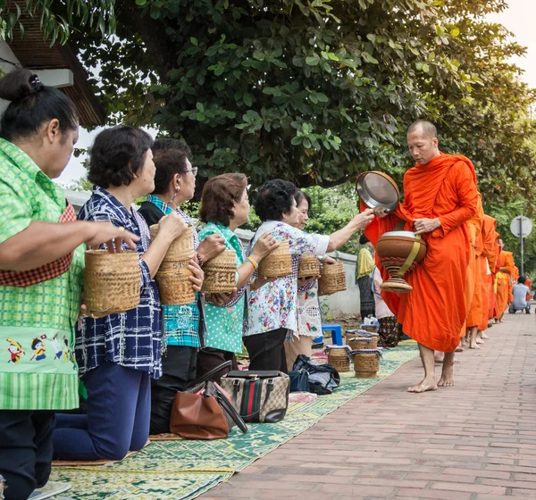 Monjes no identificados caminan para recoger limosnas y ofrendas el 27 de octubre de 2014 Laos. Esta procesión se lleva a cabo todos los días en Luang Prabang por la mañana temprano . —  Fotos de Stock