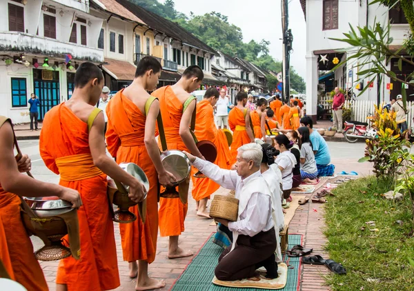 Monges não identificados caminham para coletar esmolas e oferendas em 27 de outubro de 2014 no Laos. Esta procissão é realizada todos os dias em Luang Prabang no início da manhã . — Fotografia de Stock