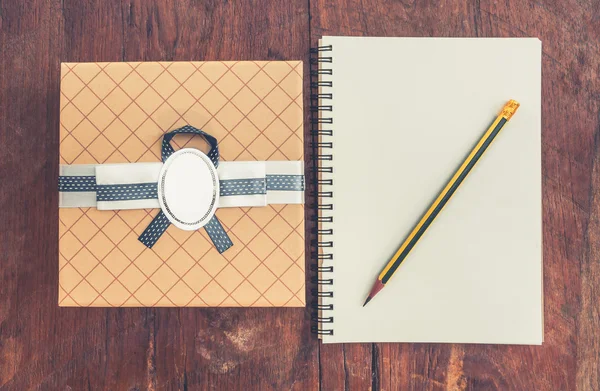 Vintage-Geschenkbox auf Holz-Hintergrund mit Notizbuch und Bleistift. — Stockfoto