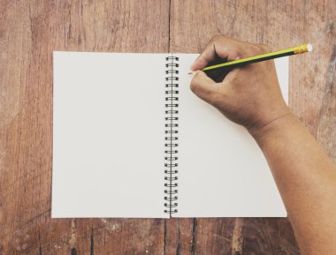 Human hands writing on blank pages of opened vintage book 