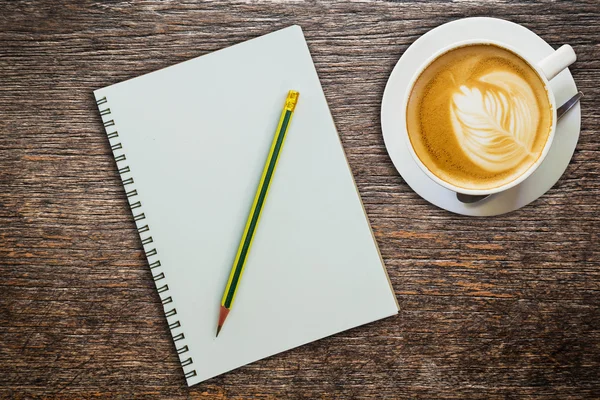 Above coffee and notebook with pencil on wood texture — Stock Photo, Image