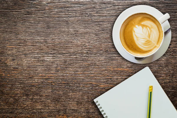 Above coffee and notebook with pencil on wood texture — Stock Photo, Image