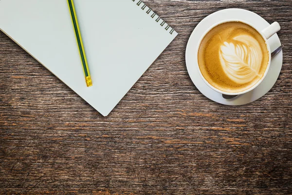 Above coffee and notebook with pencil on wood texture — Stock Photo, Image