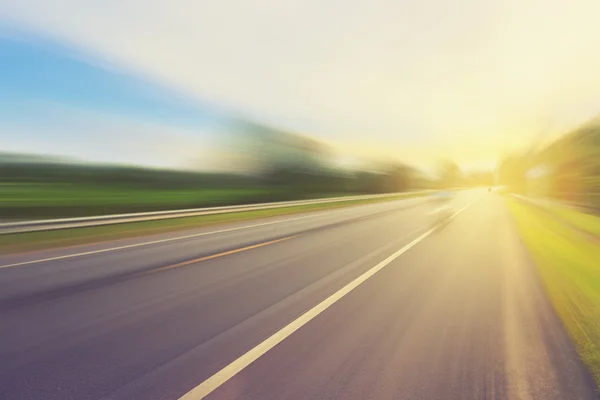 Empty asphalt road in motion blur and sunlight with vintage tone — Stock Photo, Image