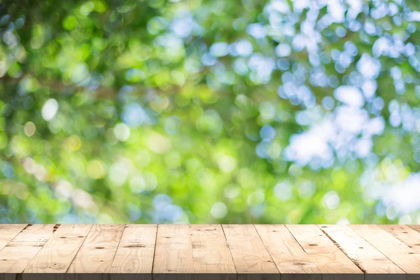 Tavolo in legno prospettiva e foglia verde bokeh offuscata per naturale — Foto Stock