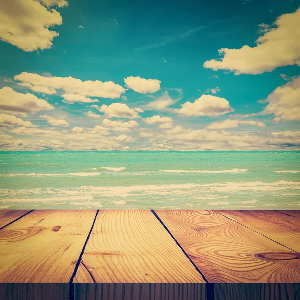 Stół z drewna i piasek plaża morze błękitne niebo chmury rocznika tonu — Zdjęcie stockowe