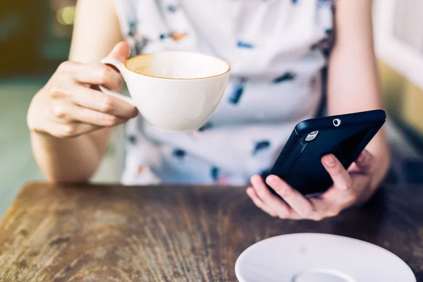 Nära håll handen kvinna med smartphone i kafé med djup o — Stockfoto