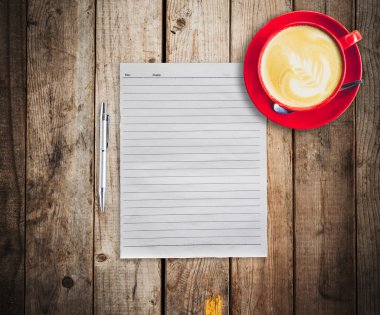 boş kağıt ve kalem ile ahşap masa arka plan üzerinde kırmızı fincan kahve