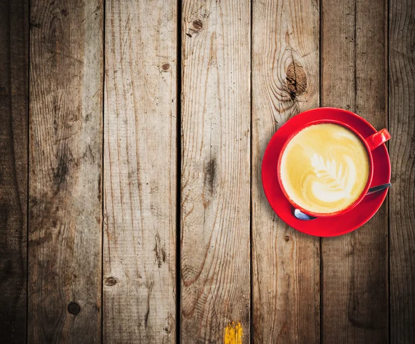 与空间的木桌上的红色杯和拿铁咖啡 — 图库照片
