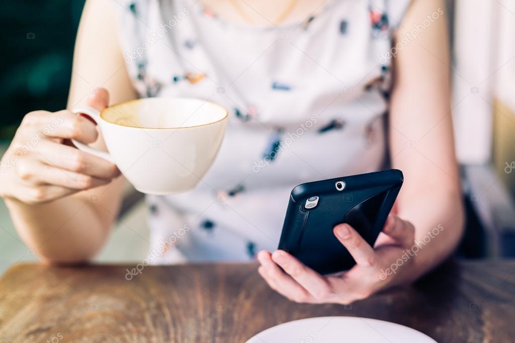 Close up of hands woman using phone in coffee shop with depth of