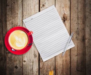 boş kağıt ve kalem ile ahşap masa arka plan üzerinde kırmızı fincan kahve