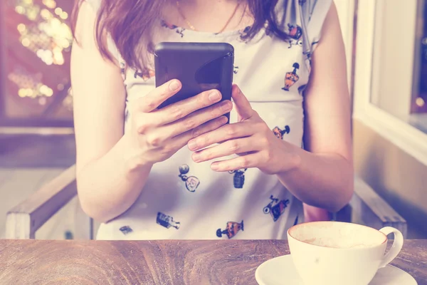 Hand kvinna med smartphone i kaféet och mjukt ljus — Stockfoto