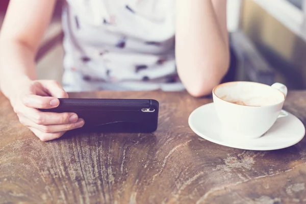 使用智能手机中的咖啡厅，柔和的光线的手女人 — 图库照片
