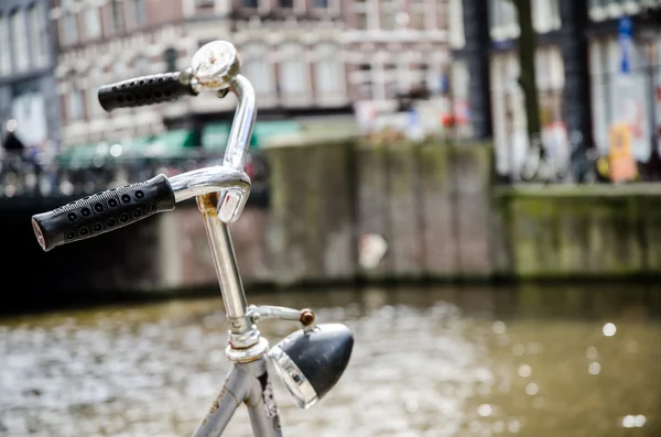 Pyörä Amsterdamissa kanavalla taustalla — kuvapankkivalokuva
