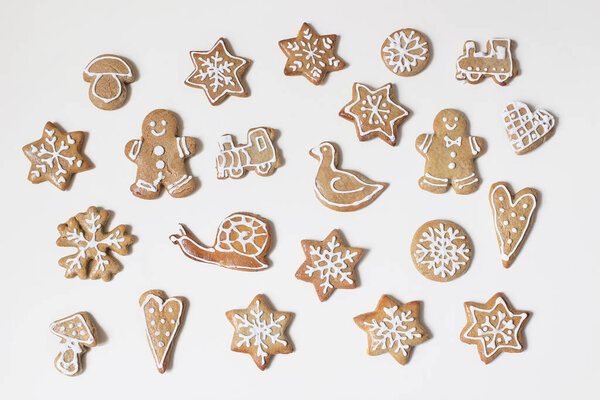 Christmas food pattern. Decorative winter composition of various gingerbread cookies with sugar icing isolated on white table background. Hearts, stars and gingerbread man. Flat lay, top view.