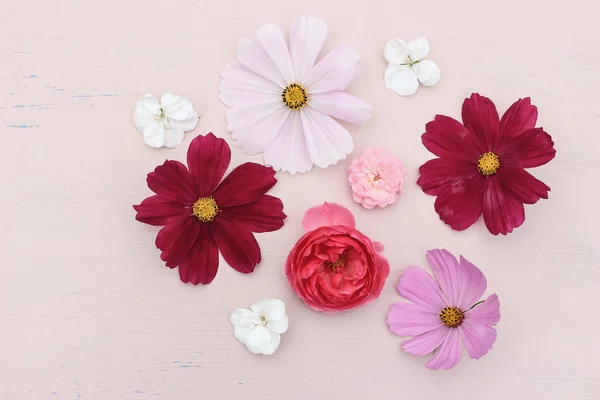 Spring or summer styled stock photo. Feminine composition with pink rose, cosmos and geranium flowers on grunge pink table background. Floral pattern. Natural, flat lay, top view. — Stock Photo, Image