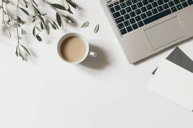 Yaz çalışma alanı kompozisyonu. Boş tebrik kartı maketi sahnesi. Bir fincan kahve, zeytin dalı ve beyaz masa arkasına izole edilmiş dizüstü bilgisayar. Düz yerde, üst tarafta. Blogger tasarımı. Merkez Ofis.