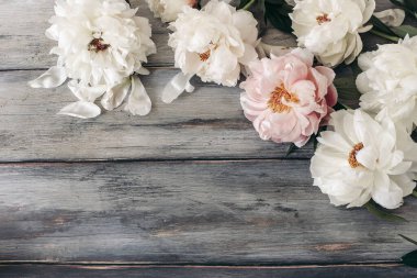 Dekoratif çiçek çerçevesi, pembe ve beyaz şakayık çiçeklerinden yapılmış pankart. Eski gri ahşap masa arka planı. Boş kopyalama alanı. Düz yerde, üst tarafta. Blog için resim. Yaz düğünü ya da doğum günü konsepti.