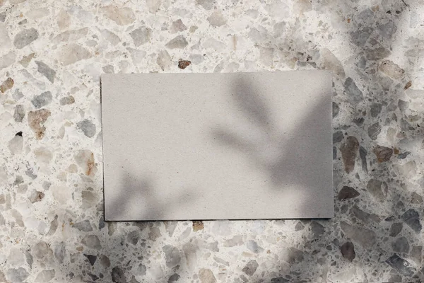 Blank beige business cards mockup on terazzo background in sunlight. Marble stone texture, tree leaf shadows overlay. Modern template, branding identity. Summer vacation design. Flat lay, top view. — Foto de Stock