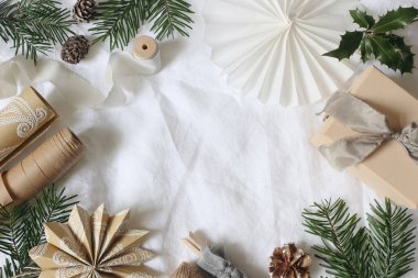Noel hediyesi paketleme natürmort. El işi kağıt, doğal süslemeler, köknar dalları, koniler, beyaz kumaş şeritleri. Tatil afişi, kopyalama alanı. DIY Paketleme, İskandinav tarzı arka plan. Flatlay, üst görünüm