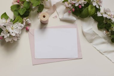 Boş yatay tebrik kartı, pembe zarf. Beyaz elma çiçekleri, çiçek çelenkleri, ipek kurdele. Düğün davetiyeleri, kırtasiyeler, selamlar, bahar mesajları için güzel bir doğum günü modeli.