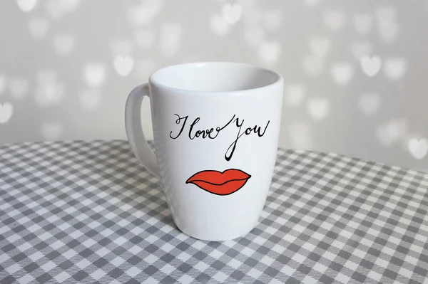 White cup with hand drawn I love you text and blurred background with heart shaped bokeh lights — Stock Photo, Image