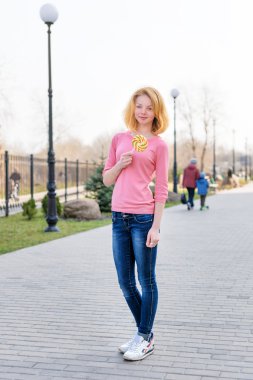 Redhead beautiful young woman holding colorful lollipop. Pretty girl having fun outdoors.