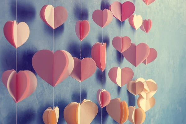 Colorful hearts paper garland hanging on the wall. Romantic Valentine's day background. Instagram style toned photo with copy space for your text. — Stock fotografie