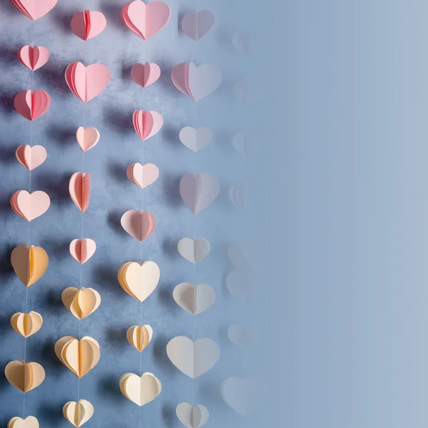 Bunte Herzen Papiergirlanden hängen an der Wand. Der Hintergrund des romantischen Valentinstages. Foto im Instagram-Stil mit Kopierplatz für Ihren Text. — Stockfoto