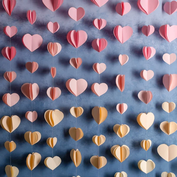 Bunte Herzen Papiergirlanden hängen an der Wand. Hintergrund des romantischen Valentinstages. — Stockfoto