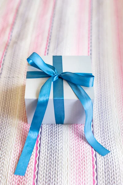 Scatola regalo con fiocco blu su sfondo tessile carino . — Foto Stock