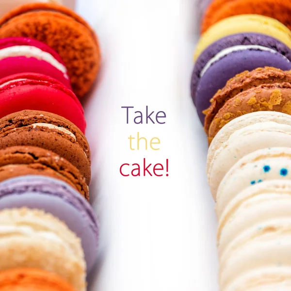 Traditional french colorful macaroons in a rows in a box with words Take The Cake.