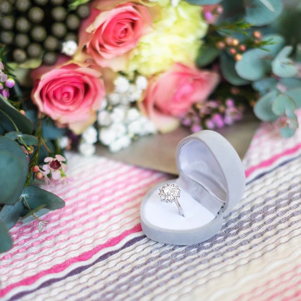 Verlovingsring in de vak op de achtergrond wazig bloemen. — Stockfoto