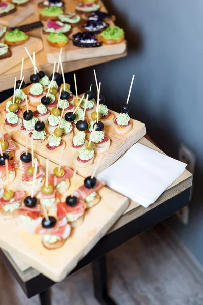 Bandeja de madera de aperitivos en la mesa de centro de la plataforma en el banquete con jamón, crema de mantequilla y aceitunas. Enfoque selectivo . —  Fotos de Stock