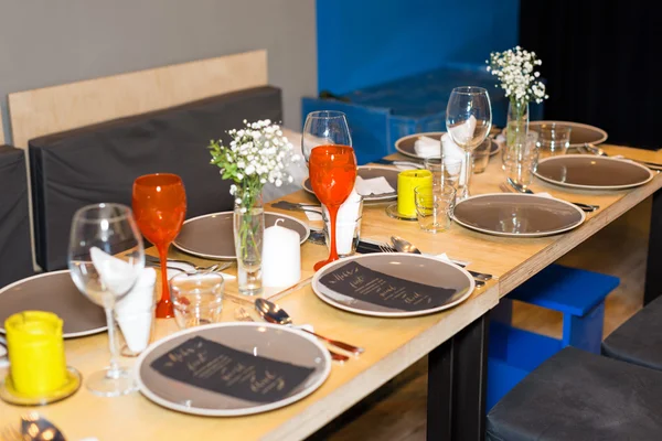 Decorated table ready for dinner. Beautifully decorated table set with flowers, candles, plates and serviettes for wedding or another event in the restaurant.