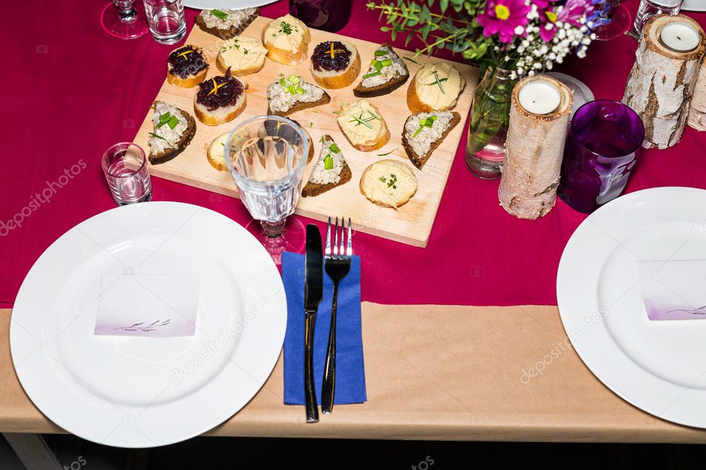 Decorated table ready for dinner. Beautifully decorated table set with flowers, candles, plates and serviettes for wedding or another event in the restaurant.