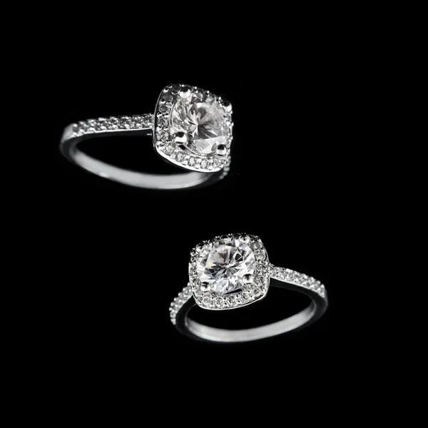 Luxury jewellery. White gold or silver engagement rings with diamonds closeup on black background. Selective focus. — Stockfoto