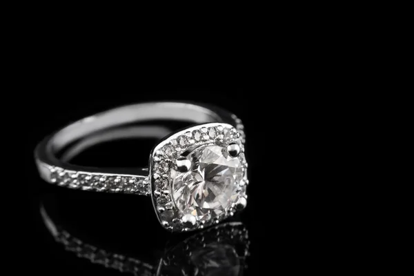 Luxury jewellery. White gold or silver engagement ring with diamonds closeup on black glass background. Selective focus. — Stock Photo, Image