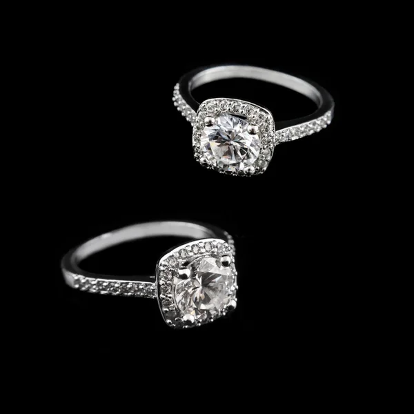 Luxury jewellery. White gold or silver engagement rings with diamonds closeup on black background. Selective focus.
