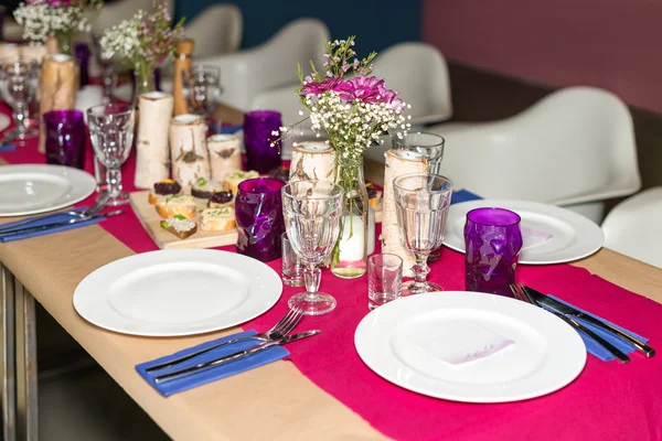 Decorated table ready for dinner. Beautifully decorated table set with flowers, candles, plates and serviettes for wedding or another event in the restaurant.