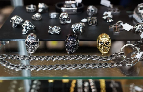 Variedad de joyas en escaparate. Anillos en forma de sculls en soporte para la venta . — Foto de Stock