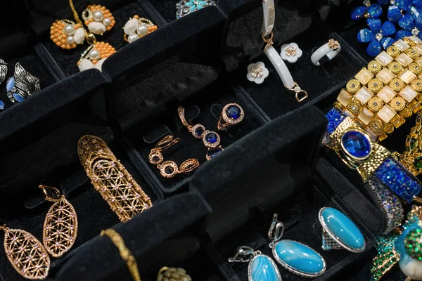 Variedad de joyas en escaparate. Anillos con gemas de colores y anamel en soportes de terciopelo en venta . — Foto de Stock