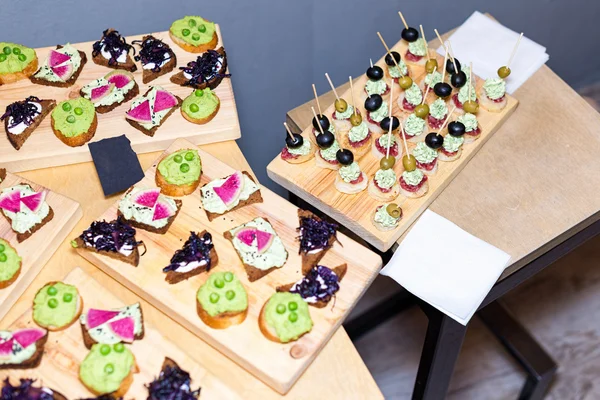 Bandeja de madera de aperitivos en la mesa de centro de la plataforma en el banquete con jamón, crema de mantequilla y aceitunas . —  Fotos de Stock