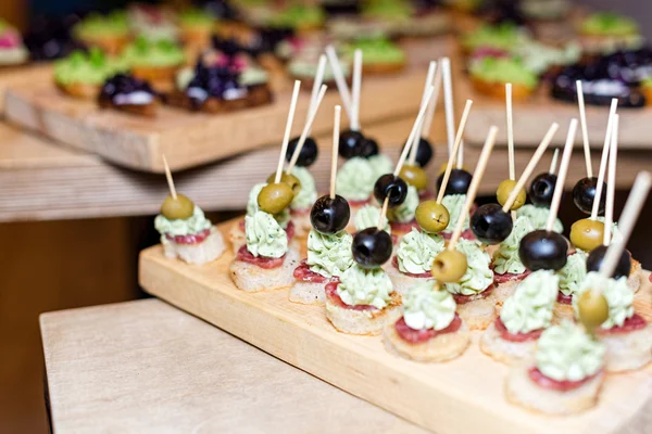 Bandeja de madera de aperitivos en la mesa de centro de la plataforma en el banquete con jamón, crema de mantequilla y aceitunas. Enfoque selectivo . —  Fotos de Stock
